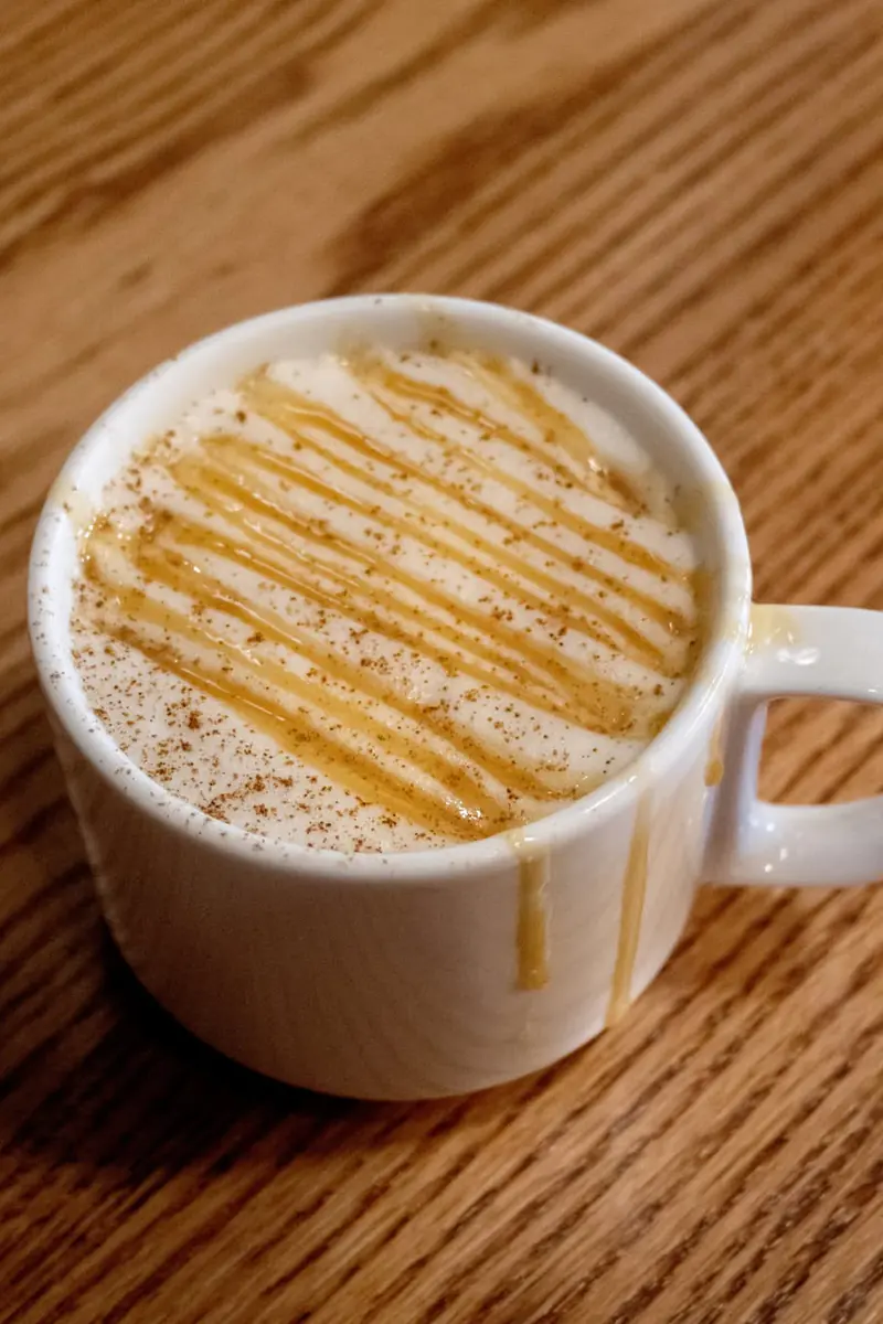 Caramel Apple Chai with caramel drizzle and cinnamon in a white mug