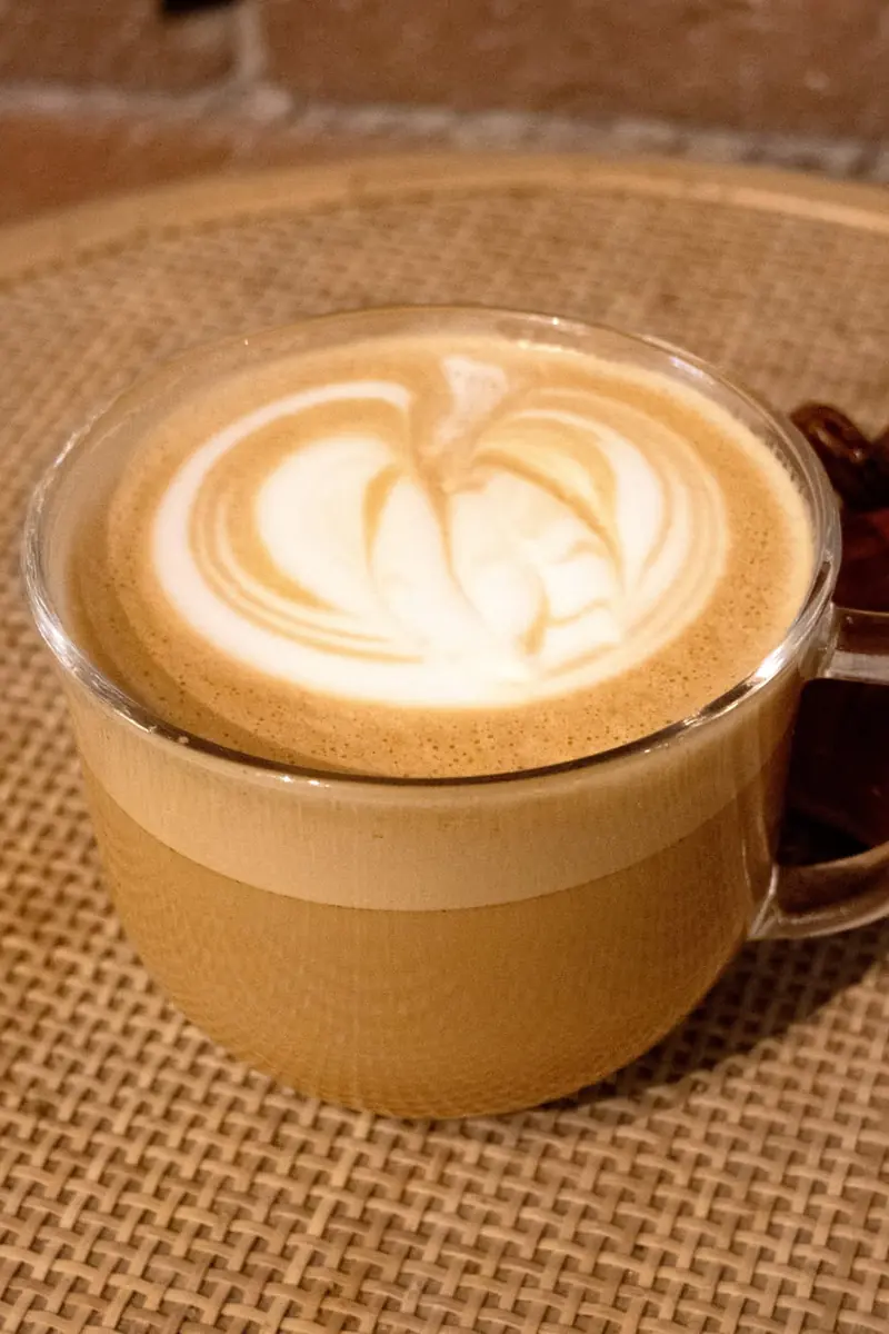 Pumpkin Spice Latte with latte art in a clear glass mug