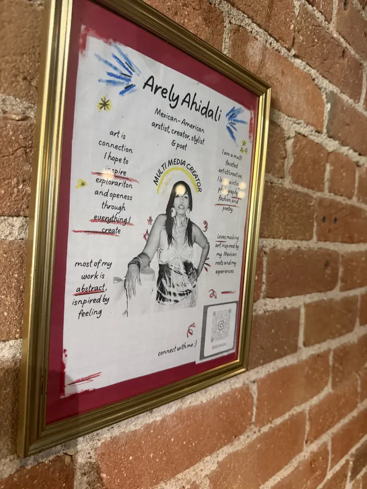Framed artist statement for Arely Ahidali, multimedia creator, hanging on the brick wall