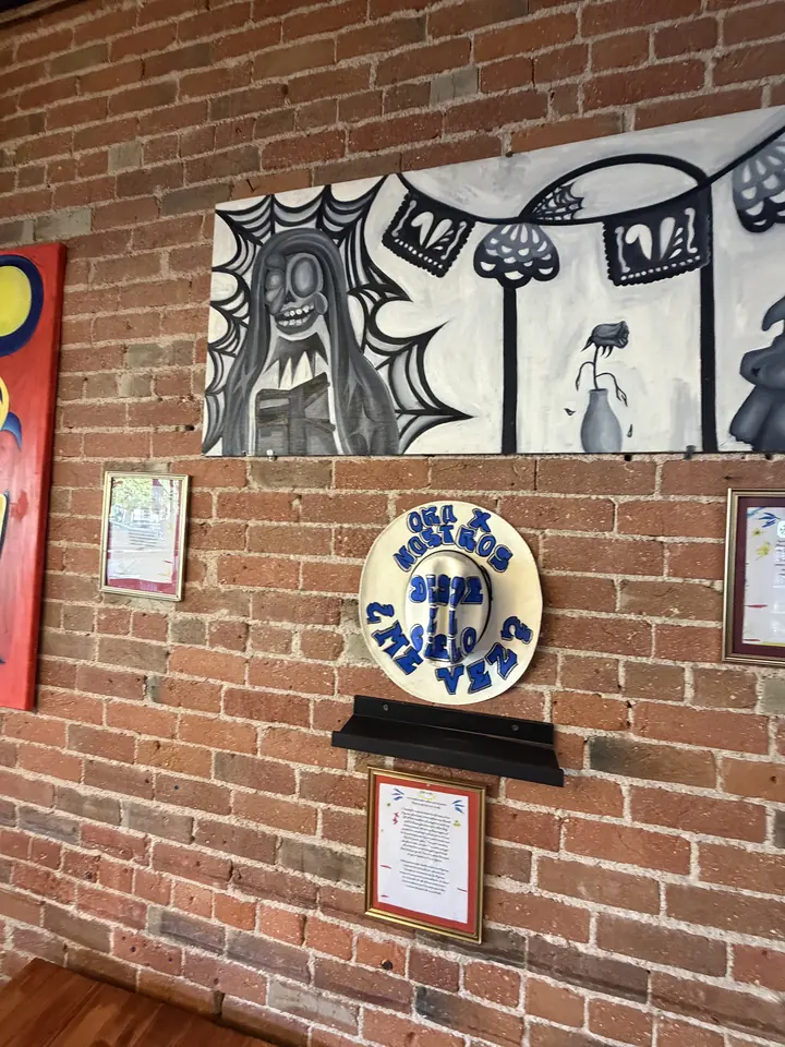 Black and white mural panel by Arely Ahidali with a skeleton figure and papel picado banners