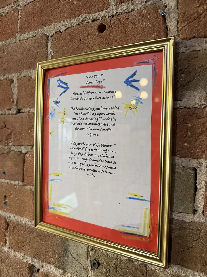 Framed bilingual card describing Love Blind (Amor Ciego) in English and Spanish