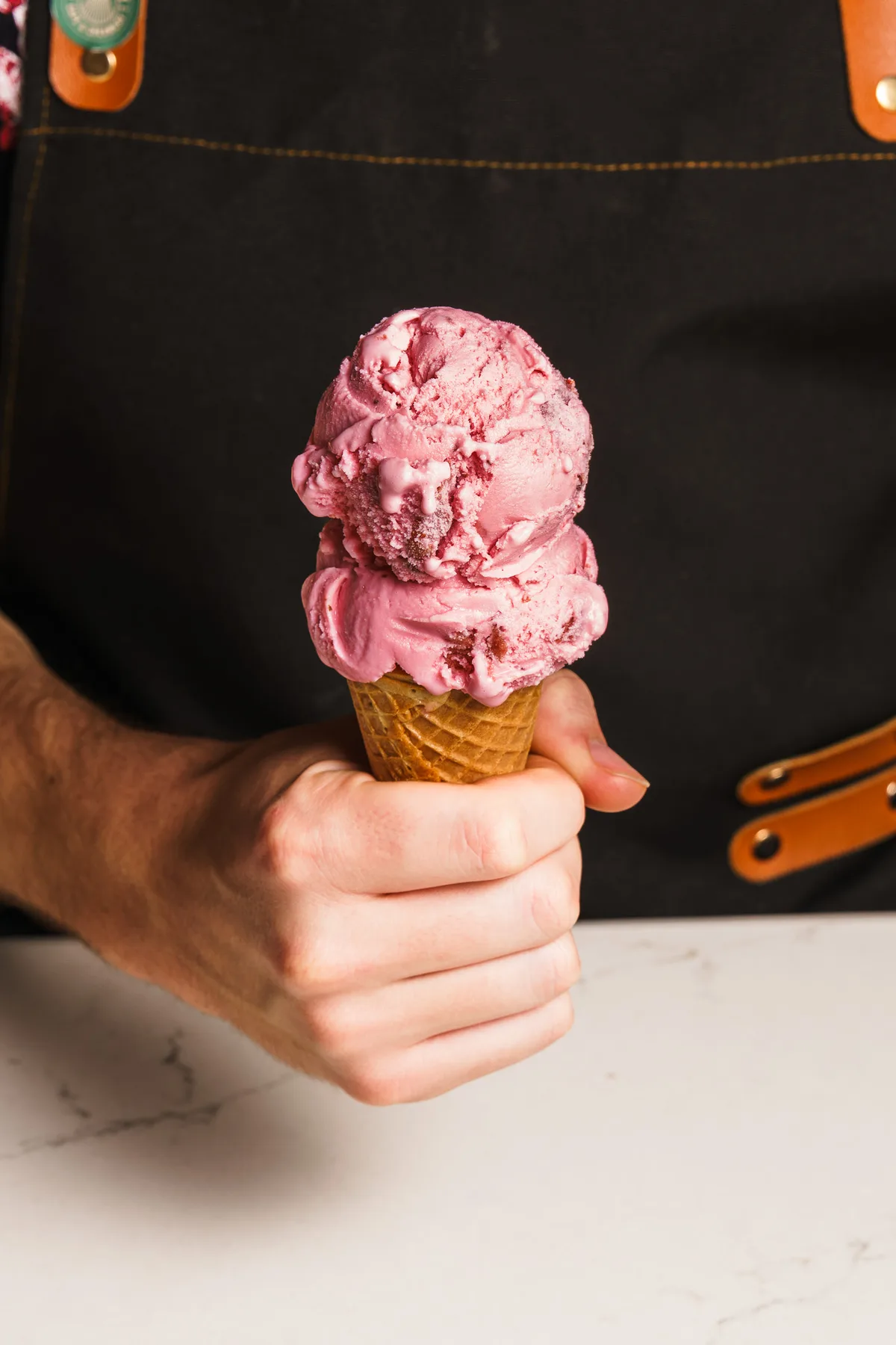 Hand holding a strawberry ice cream cone